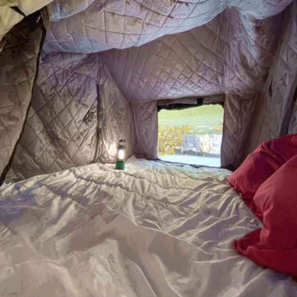 Vue intérieure d'une tente de toit avec isolation hivernale, doublure matelassée et coussins, offrant chaleur et confort pour 2 à 3 personnes.