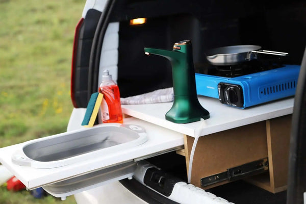 Installation de cuisine de camping portable dans le coffre de la voiture avec évier, cuisinière et espaces de rangement.